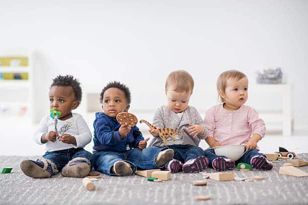 Babies playing with toys indoors at a daycare.